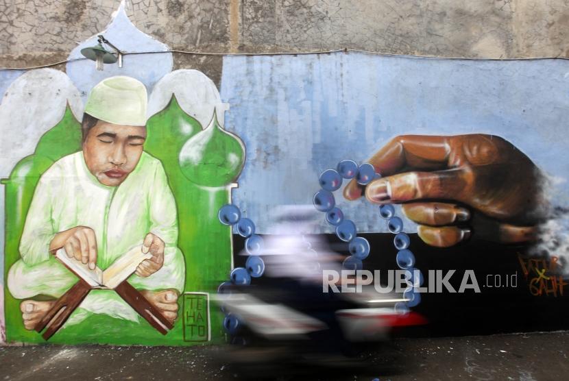 Pengendara motor melintas didepan dinding mural bertema ramadhan di Gang Abdul Jabar, Jagakarsa, Jakarta, Senin (28/5).