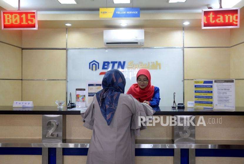 Petugas melayani transaksi nasabah di kantor layanan BTN Syariah, Jakarta.