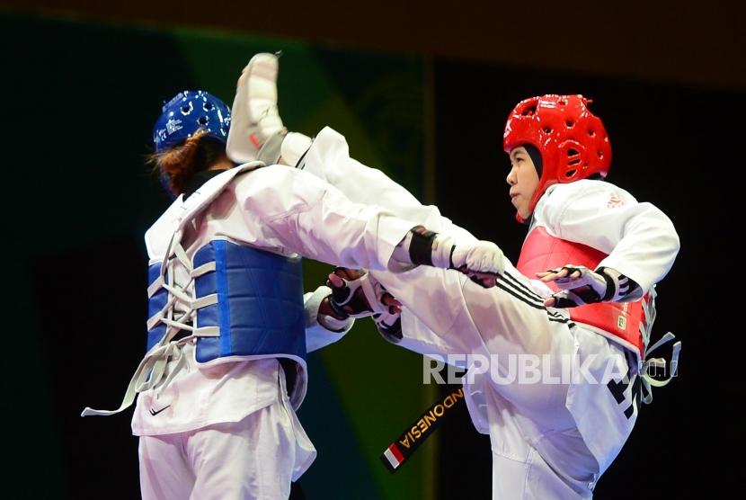 Atlet Taekwondo Putri Indonesia Shaleha Fitriana Yusuf (merah) melancarkan tendangan ke arah lawannya dari Philipina Darlene Mae Arpon (biri) pada babak final kelas under 67 kg pada ajang  Invitation Tournament Asian Games 18 di Jakarta, Ahad (11/2).