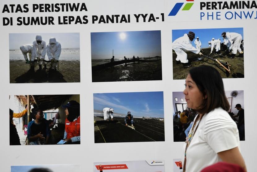 Karyawan melintasi foto-foto dokumentas penanganan kebocoran Sumur Lepas Pantai YYA-1 di Kantor Pusat Pertamina, Jakarta, Jumat (20/9/2019).