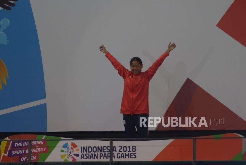 Selebrasi perenang Syuci indriani  diatas podium usai memenangkan final  Para Swim  100 Meter gaya dada di Asian Para Games, Stadion Akuatik, Jakarta, Senin (8/10).