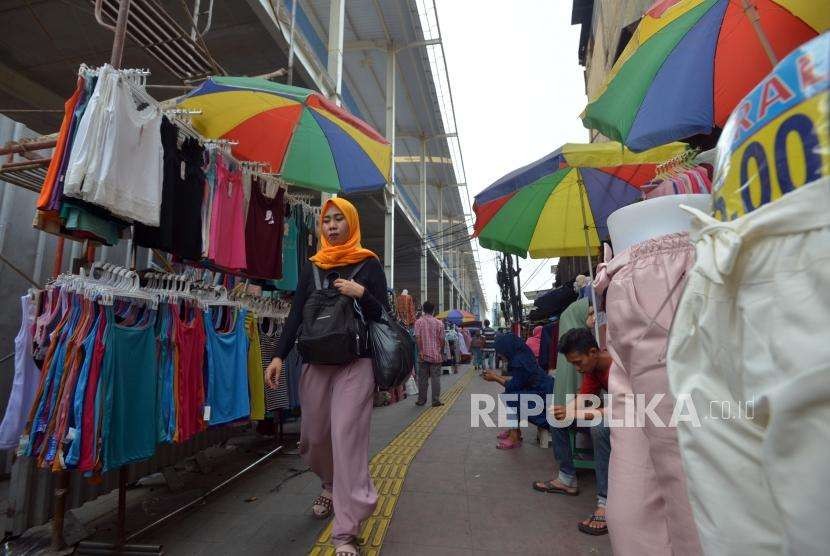 Warga melintas didekat barang dagangan para pedagang di Jalan Jatibaru, Tanah Abang, Jakarta, Kamis (27/9).