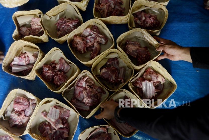 Panitia merapikan besek bambu berisi daging kurban yang akan dibagikan di Masjid Nurul Hilal, Cibulan, Jakarta, Ahad (11/8).