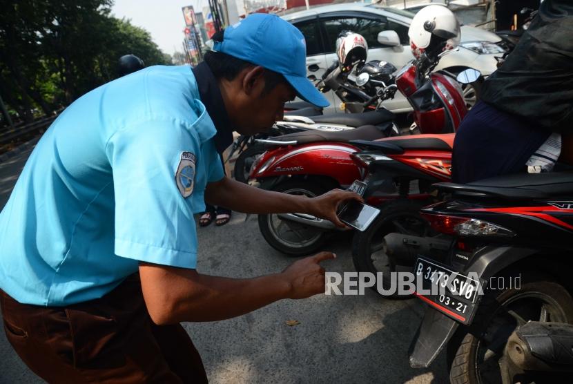 Juru parkir melakukan pemotretan nomor kendaraan bermotor untuk melakukan  pembayaran parkir di jalan danau sunter, Jakarta Utara, Jumat (29/6). (Ilustrasi)