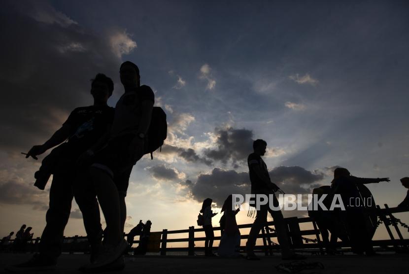Pengunjung menikmati suasana pantai saat liburan di Pantai Ancol, Jakarta, Jumat (30/3).