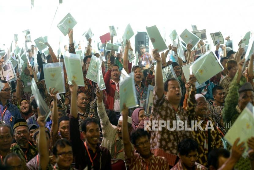  Warga mengangkat sertifikat tanah usai diserahkan oleh Presiden Joko Widodo di Sentul, Bogor, Jawa Barat, Selasa (6/3).