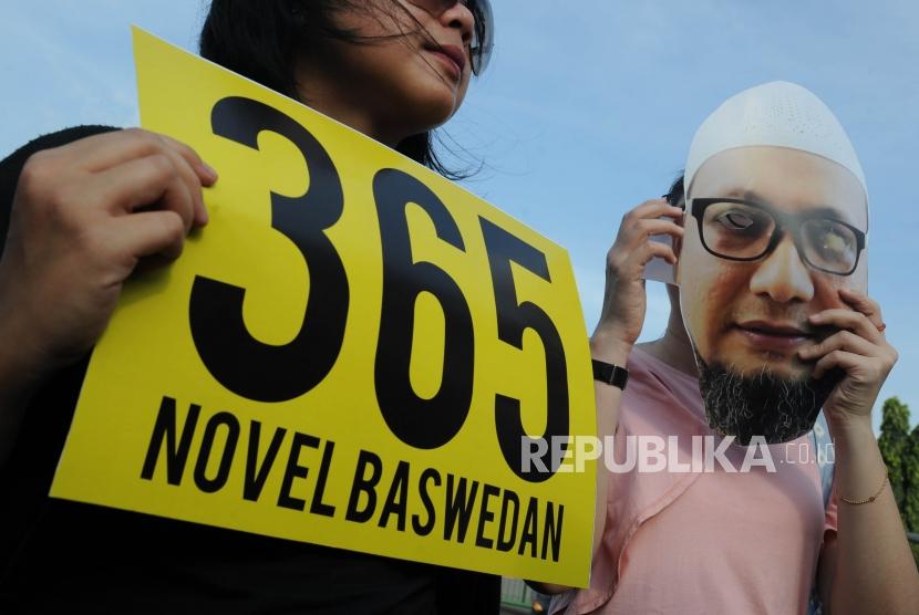 Aktivis Anti Korupsi membawa poster bergambarkan Novel Baswedan dalam rangka peringatan 1 tahun kasus Novel Baswedan di depan Istana Merdeka Jakarta, Rabu (11/4).