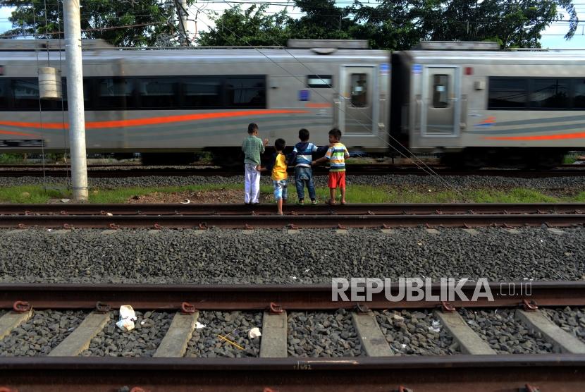 Anak-anak menunggu kereta melintas diatas rel yang belum dioperasikan di kawasan Klender, Jakarta, Kamis (11/4), PT KAI akan mulai mengoperasikan jalur rel dwi ganda (double-double track) lintasan Cakung-Jatinegara yang terbentang sepanjang 9,5 kilometer itu pada Jumat (12/4).