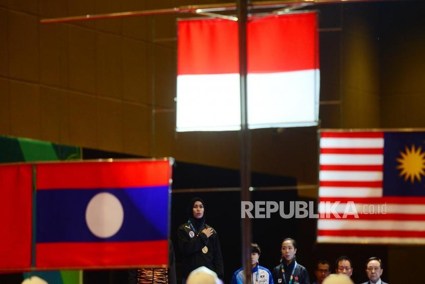 Atlet putri Taekwondo Indonesia Defia Rosmaniar memberikan hormat kepada bendera Merah Putih usai pengalungan Medali Emas usai memenangkan babak final perorangan Poomsae di event Invitation Torunament Asian Games 18 di Jakarta, Sabtu (10/2).
