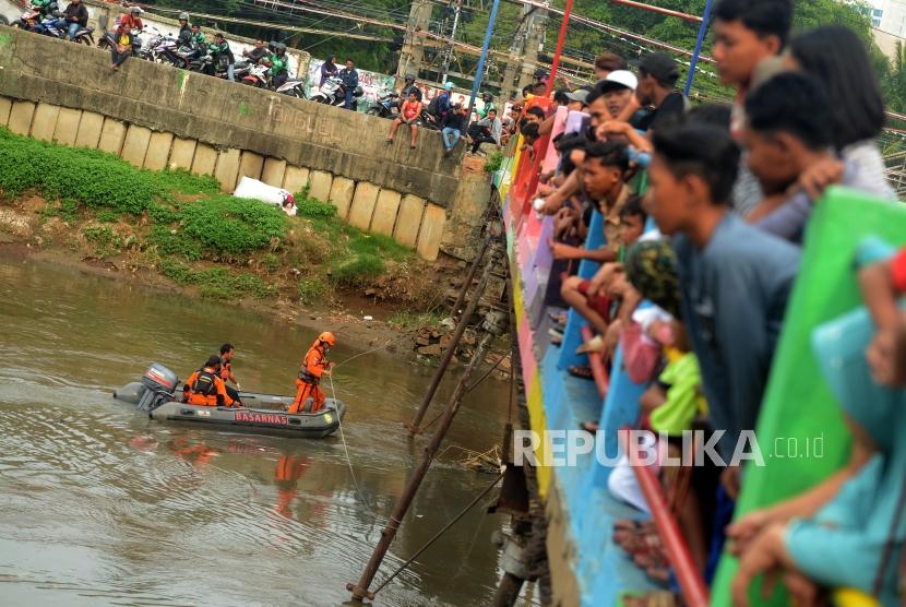 Suasana warga saat melihat proses evakuasi pencarian korban tenggelam di aliran Banjir Kanal Barat (BKB), Jatipulo, Palmerah, Jakarta Barat, Rabu (7/11).