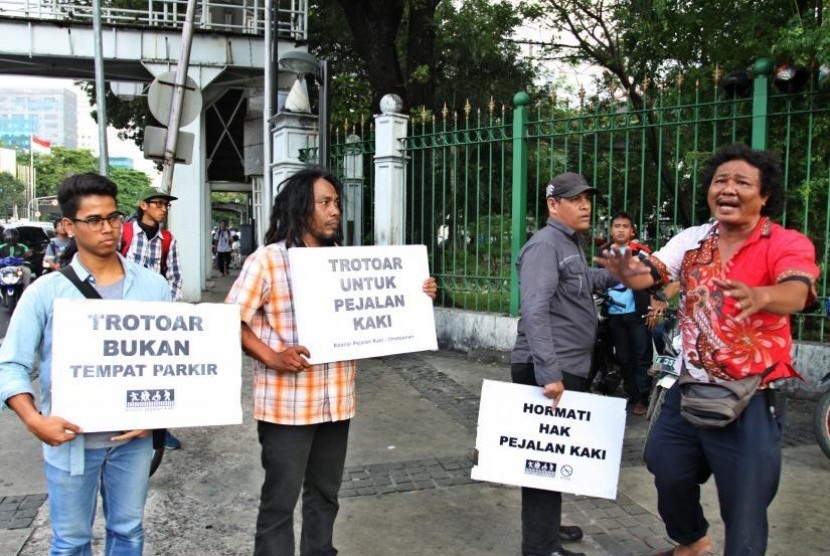 Aktivis Koalisi Pejalan Kaki (KPK) melakukan aksi di sepanjang trotoar kawasan Monas, Jakarta, Jumat (28/7). Aksi tersebut dilakukan untuk mengembalikan fungsi trotoar sebagai tempat bagi pejalan kaki yang sering diokupasi oleh kendaraan bermotor. ANTARA FOTO/ Reno Esnir/pd/17