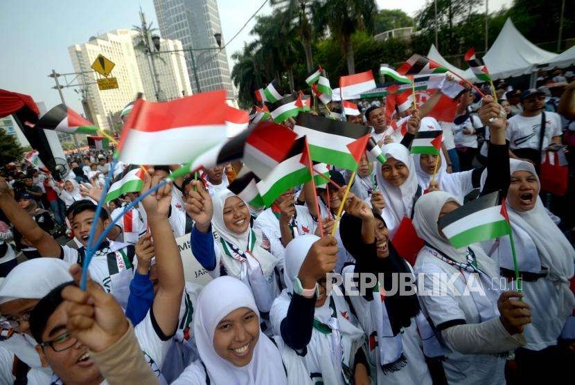Peserta jalan santai  Walk for Peace and Humanity  mengibarkan bendera merah putih dan palestina  di kawasan car free day (CFD) Jakarta, Ahad (14/10).