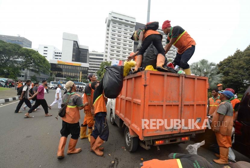 Petugas PPSU membersihkan sampah pasca aksi reuni 212 di kawasan Tugu Tani, Jakarta, Ahad (2/12).