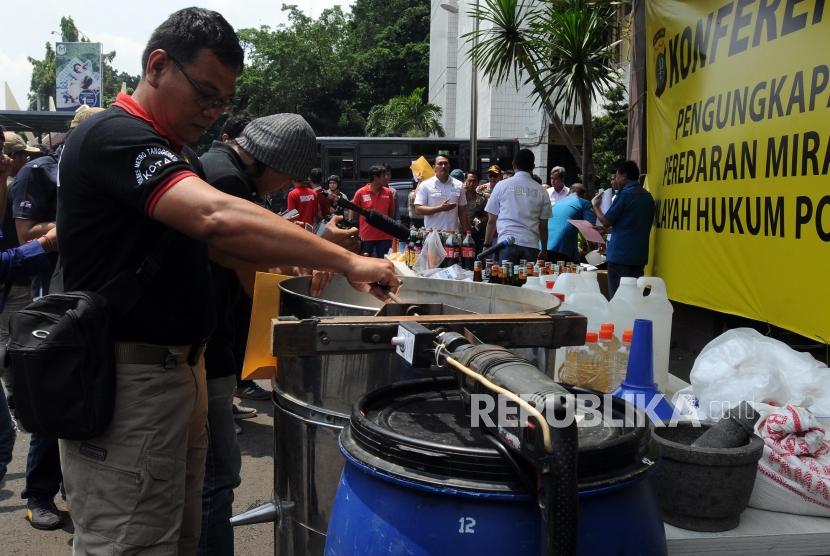 Sejumlah petugas kepolisian merapihkan barang bukti alat pembuat minuman keras oplosan di Polres Jakarta Selatan, Kebayoran Baru, Jakarta Selatan, Rabu (11/4).