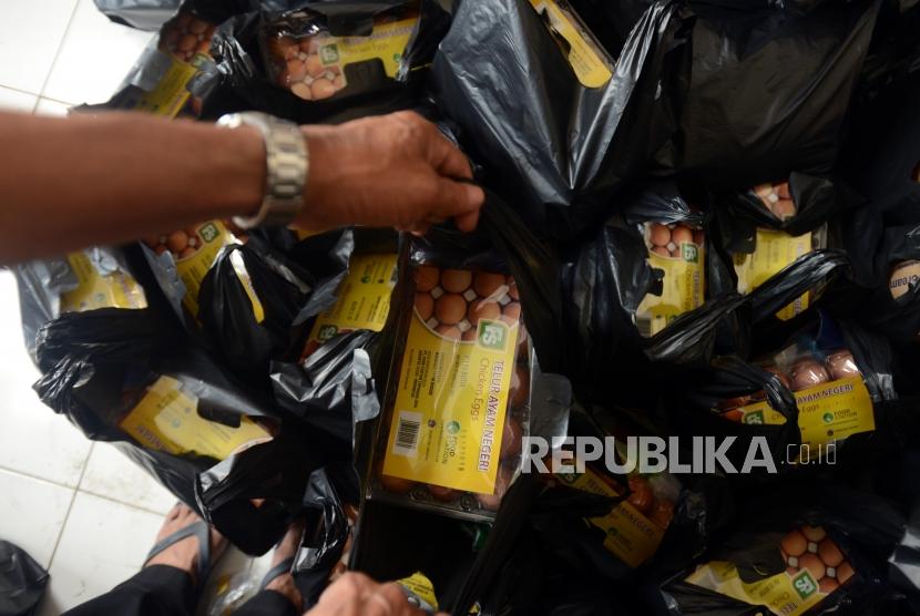 Petugas mengambil plastik untuk diberikan kepada warga saat pasar murah di Pasar Teluk Gong, Jakarta, Rabu (28/11).