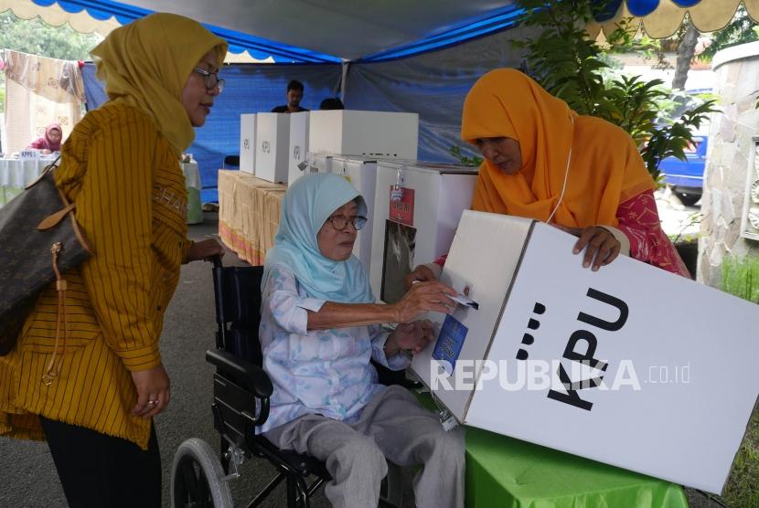 Seorang pemilih lansia dibantu petugas KPPS memasukkan surat suaranya kedalam kotak suara di TPS 65, kelurahan Sunter Jaya, Jakarta, Rabu (17/4).