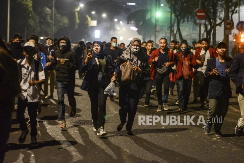 Sejumlah mahasiswa berlari usai ditembakan gas air mata saat terjadi kericuhan di depan Gedung DPR, Jakarta, Selasa (24/9).
