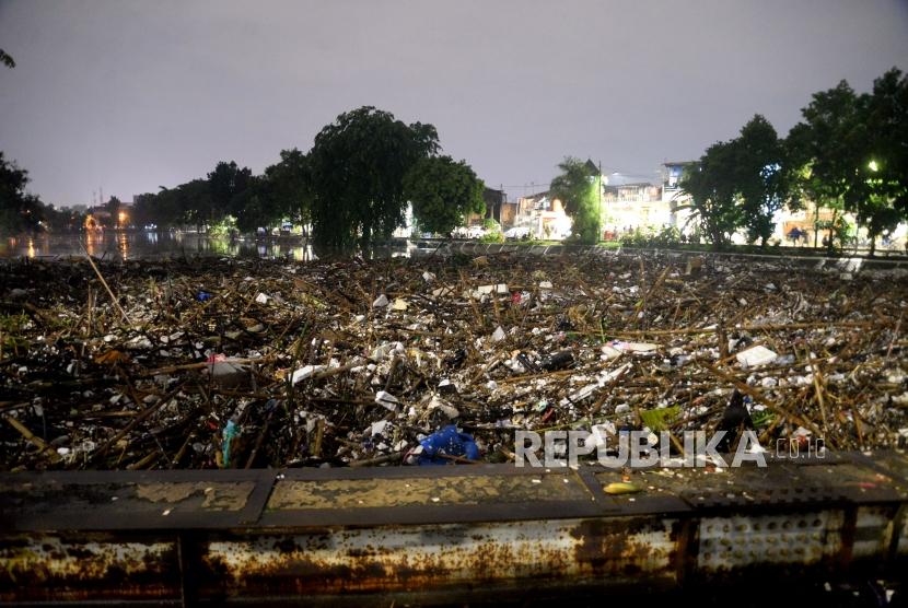 Warga melihat sampah yang terbawa luapan air sungai ciliwung di Jembatan Kampung Melayu, Jakarta, Senin (5/2) malam.
