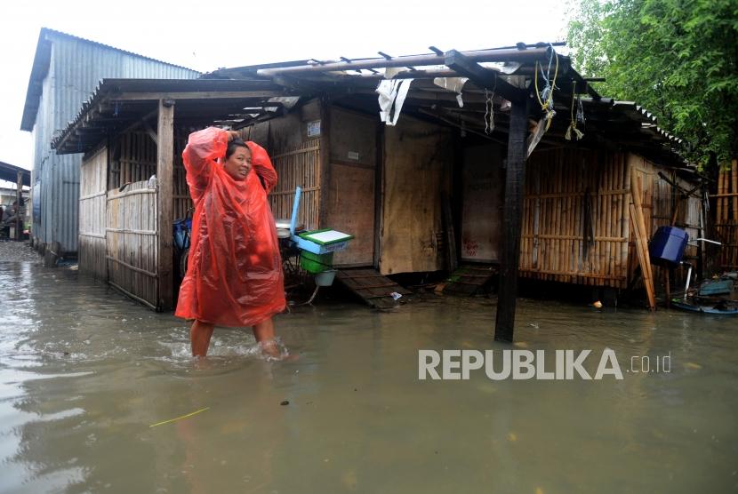 Warga melintasi genangan air saat terjadi banjir rob di kawasan Muara Angke, Jakarta Utara, Selasa (22/1).