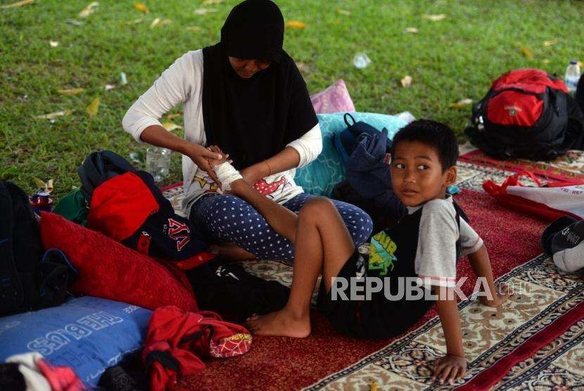 Pengungsi merawat anaknya yang terluka akibat bencana alam gempa bumi dan tsunami saat beraktivitas di Posko Pengungsian Rumah Dinas Gubernur, Palu, Sulawesi Selatan, Rabu (3/10).