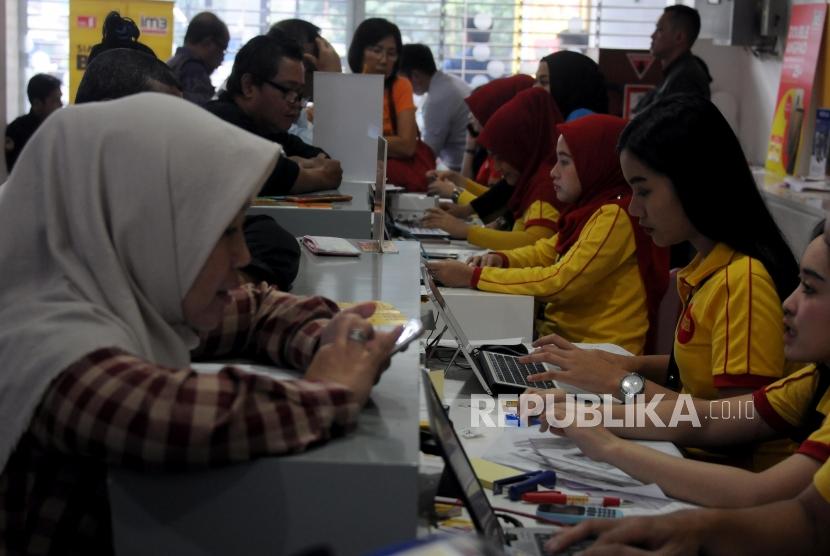 Petugas melayani antrian warga yang akan melakukan registrasi ulang kartu SIM prabayar di Galeri Indosat, Kota Bogor, Jawa Barat, Rabu (28/2).