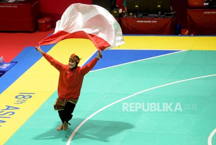 Pesilat Indoensia Puspa Arumsari berlari dengan membawa bendera merah putih usai beraksi pada final cabang pencak silat kelas artistik tunggal putri Asian Games 2018 di Padepokan Pencak Silat TMII, Jakarta, Senin (27/8).