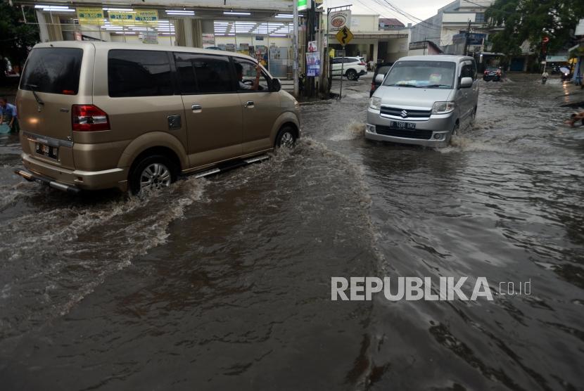 Sejumlah kendaraan melintasi genangan air di Jalan Taman Duta Pelni, Sukmajaya, Depok, Jawa Barat, Kamis (31/1).