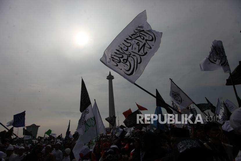 Sejumlah massa mengibarkan bendera tauhid saat mengikuti reuni aksi 212 di Lapangan Monumen Nasional, Jakarta, Ahad, (2/12).