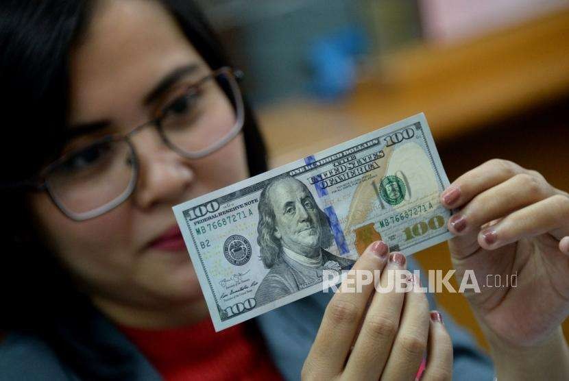 Petugas memeriksa kondisi dolar Amerika Serikat di gerai penukaran mata uang asing di Jakarta, Selasa (2/10).