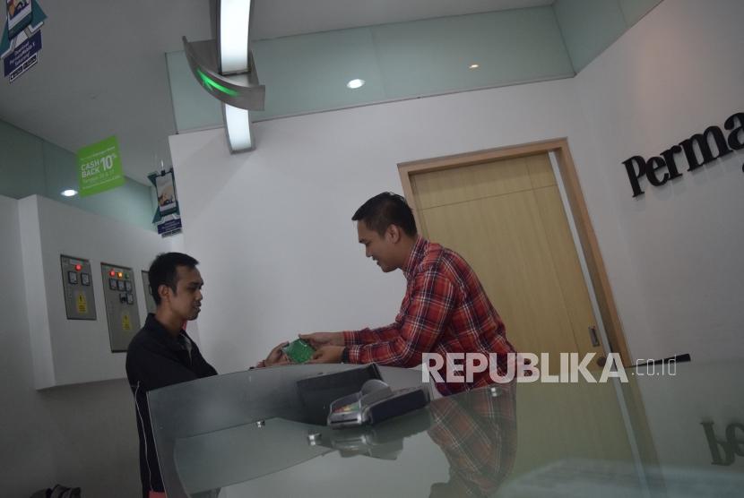 Karyawan melayani transaksi nasabah di Permata Bank Jakarta, Jumat (9/11).