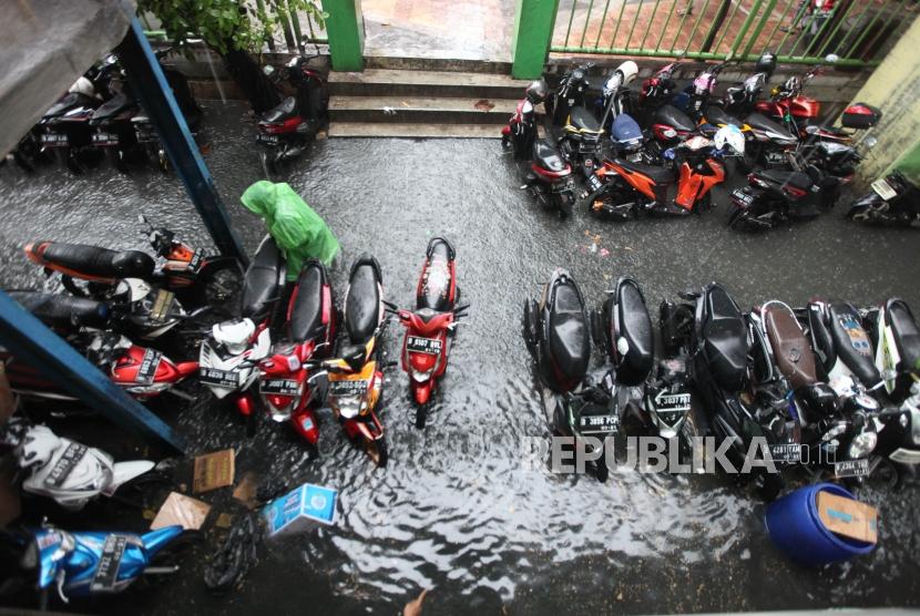 Warga melintasi genangan air di Pasar Blok G Tanah Abang, Jakarta, Senin (11/12).