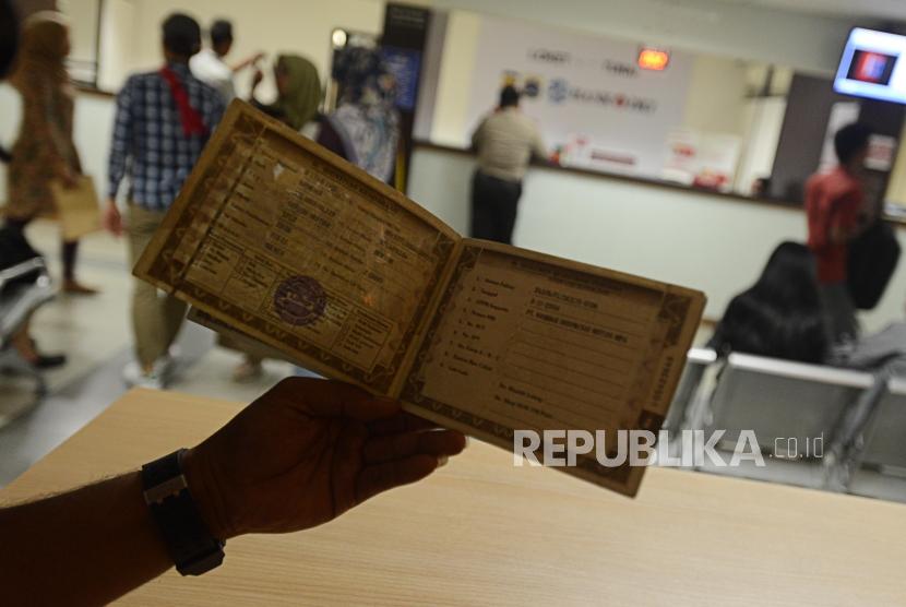Warga menujukan BPKB saat melakukan pembayaran pajak kendaraan bermotor di Kantor Samsat Polda Metro Jaya, Jakarta, Jumat (16/11).