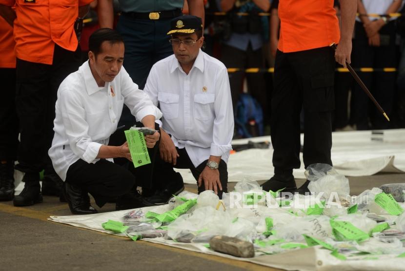 Presiden Joko Widodo (kiri) didampingi Menteri Perhubungan Budi Karya Sumadi (kanan) saat meninjau barang-barang temuan hasil pencarian pesawat Lion Air JT 610 di Dermaga JICT 2, Pelabuhan Tanjung Priok, Jakarta, Selasa (30/10).