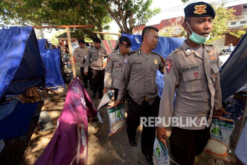 Sejumlah petugas kepolisian saat memberikan bantuan kepada pengungsi di Posko pengungsian Lapangan Masjid Agung Darussalam , Palu, Sulawesi Tengah, Jumat (5/10).