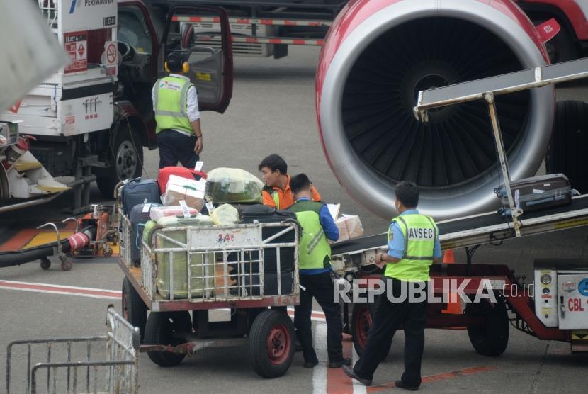 Petugas masukan barang milik penumpang ke bagasi pesawat di Bandara Internasional Soekarno,-Hatta, Tanggerang,Banten, Kamis (7/2).