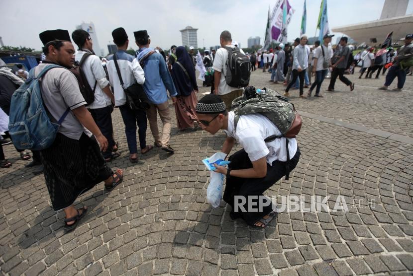 Peserta reuni aksi 212 mengumpulkan sampah seusai Reuni Aksi 212 di Lapangan Monumen Nasional, Jakarta, Ahad, (2/12).