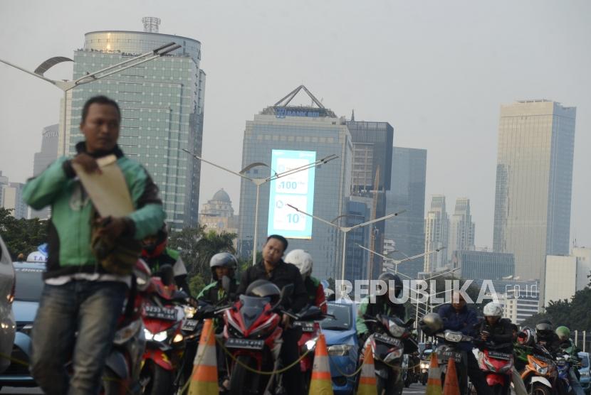 Sejumlah pengendara motor berhenti dengan latar belakang suasana gedung bertingkat yang diselimuti asap polusi di kawasan Sudirman, Jakarta, Senin (29/7).
