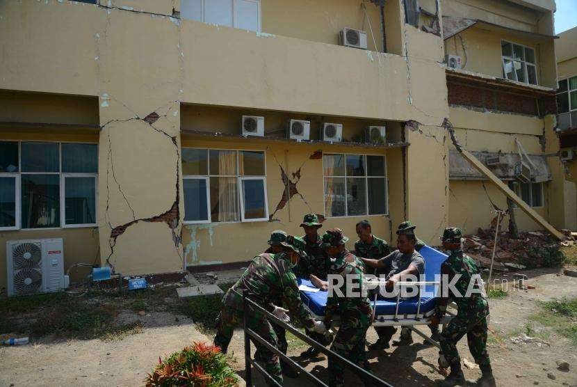 Anggota TNI membawa korban gempa bumi menuju rumah sakit lapangan di Rumah Saki Tanjung, Lombok Utara, Nusa Tenggara Barat, Rabu (8/8).