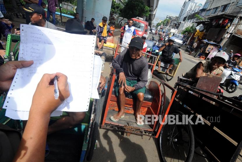 Tukang becak saat didata oleh petugas di kolong flyover Bandengan Utara, Pekojan, Tambora, Jakarta Barat, Jumat (26/1).