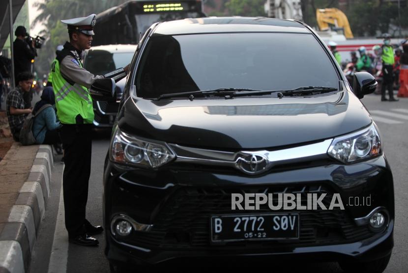 Polisi menilang pengendara bernomor polisi genap saat sistem ganjil genap di Kawasan Pancoran, Jakarta, Rabu (1/8).