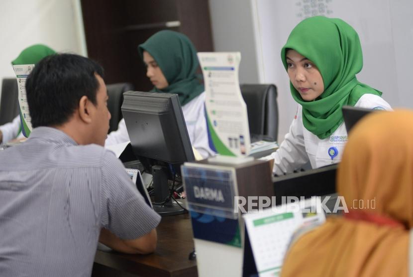Petugas Badan Penyelenggara Jaminan Sosial (BPJS) Kesehatan melayani warga di kantor BPJS Kesehatan Cabang Jakarta Selatan, Senin (2/9).