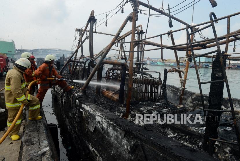 Pasca Kebakaran Kapal Muara Baru. Petugas pemadam kebakaran melakukan pendinginan terhadap kapal yang telah habis terbakar di Pelabuhan Muara Baru, Jakarta, Ahad (24/2).