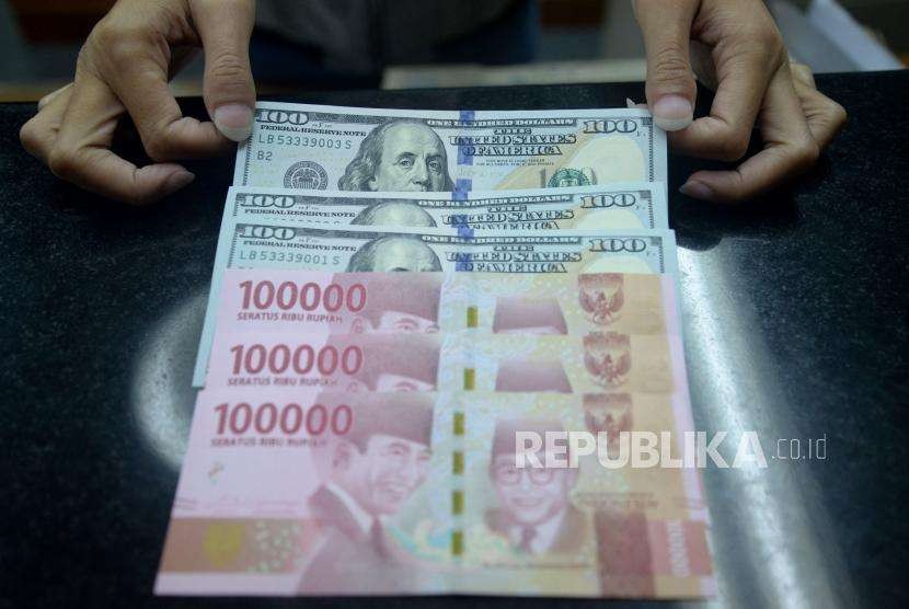 Petugas menghitung pecahan dolar Amerika Serikat dan rupiah di salah satu gerai penukaran mata uang asing di Jakarta,Ahad (2/9).