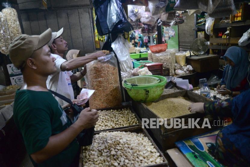 Pedagang melayani pembeli bahan makanan pokok di Pasar Senen, Jakarta, Selasa (26/12).
