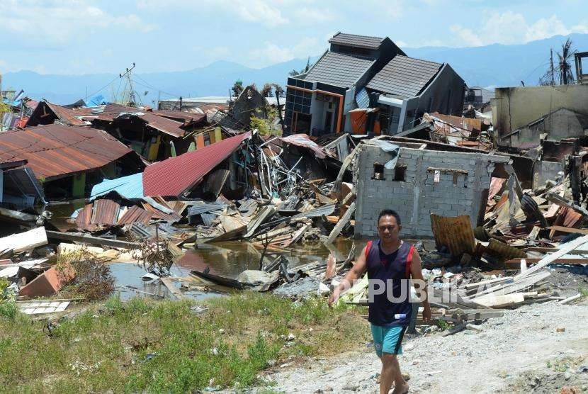 Sejumlah warga melintas didekat puing-puing bangunan di Perumnas Balaroa, Palu, Sulawesi Tengah, Senin (1/10).