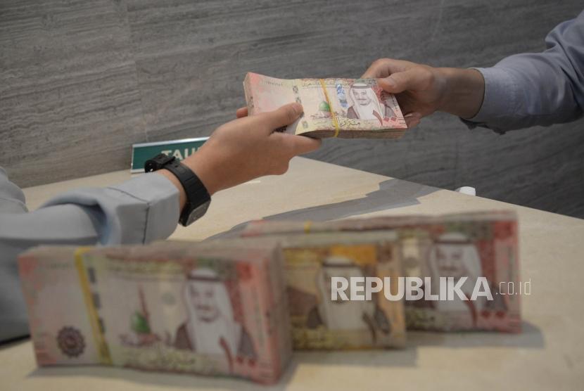 Petugas melayani nasabah yang menukarkankan uang rupiah dengan Arab Saudi  Riyal (SAR) di gerai Money Changer