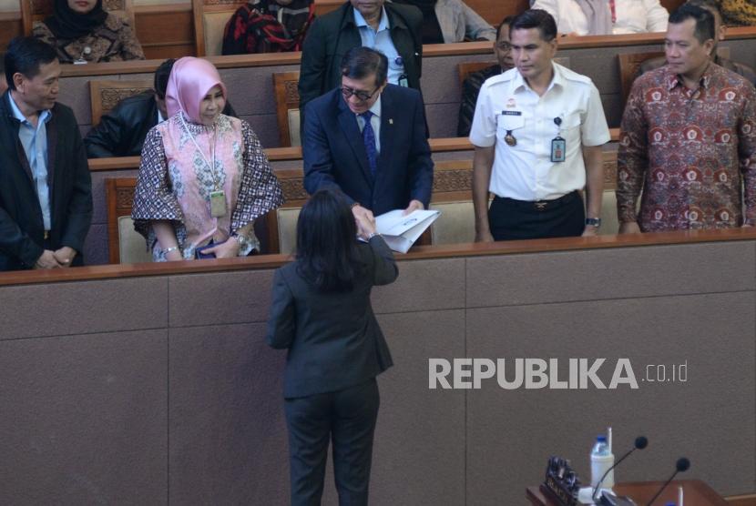 Menkumham Yasonna Laoly menerima laporan pandangan Komisi III DPR dari Wakil Ketua Komisi III DPR Irma Suryani Ranik  saat Rapat Paripurna di Kompleks Parlemen Senayan, Jakarta, Selasa (24/9).