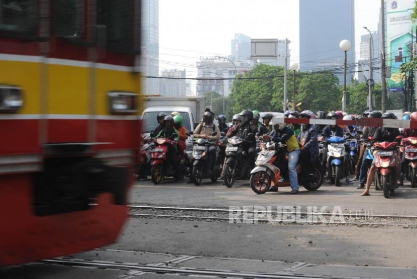 Menunggu. Pengendara kendaraan roda dua  menunggu teerbukanya pintu perlintasan kereta sebidang di Jalan K.H Mansyur, Jakarta, Rabu (1/11).