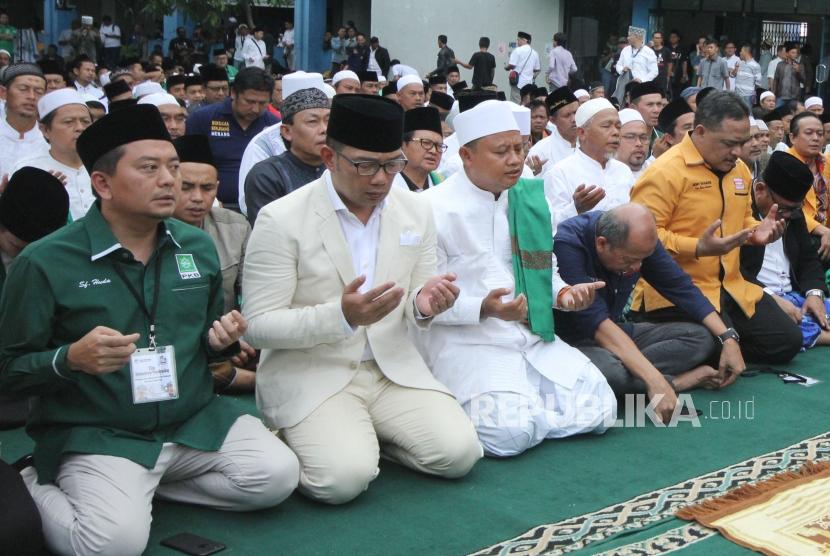 Pasangan Calon Gubernur dan Wakil Gubernur Jawa Barat Ridwan Kamil dan Uu Ruzhanul Ulum dan massa pendukungnya berdoa bersama, di halaman parkir lapangan Sidolig, Kota Bandung, Selasa (9/1).