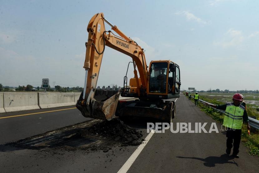 Pekerja menggunakan alat berat saat menyelesaikan perbaikan Jalan Tol Pejagan-Pemalang kilometer 316, Kabupaten Pemalang, Jawa Tengah, Selasa (7/5).